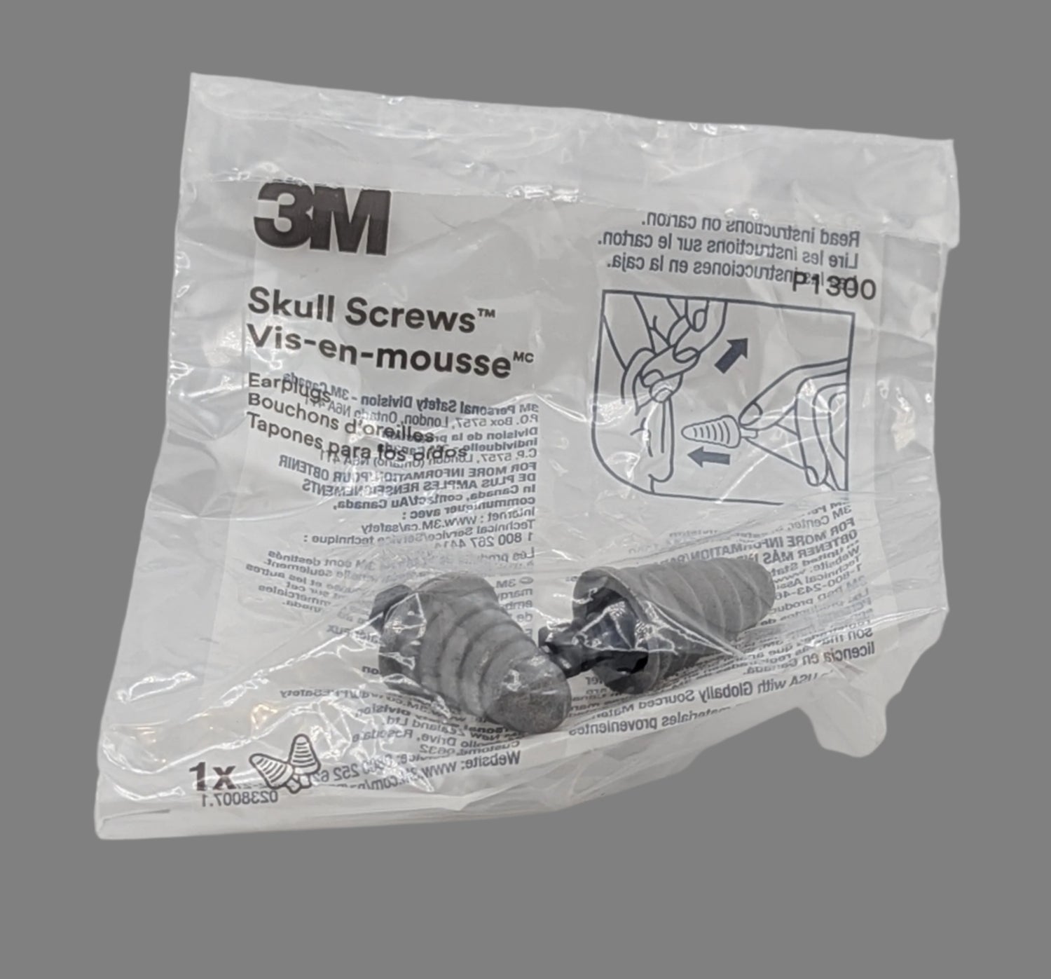 A pair of earplugs in a plastic bag in front of a gray background.